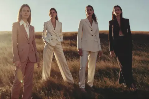 Quatre femmes en tailleurs élégants, dont un en lin textile, posent dans un champ d'herbes hautes au coucher du soleil.