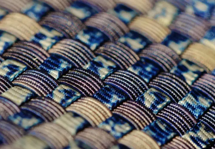 Gros plan sur un tissu intelligent aux motifs bleus et blancs entrelacés, révélant une texture complexe et des fils brillants.