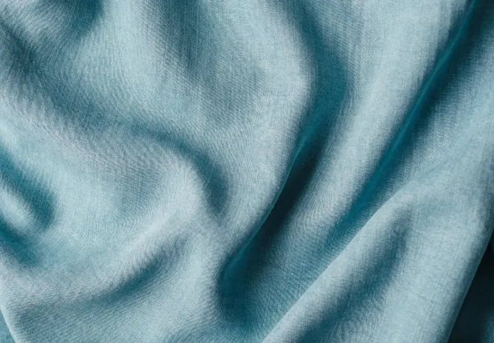 Plissé de textiles artificiels bleu pâle, évoquant la douceur et la fluidité d'une étoffe moderne.