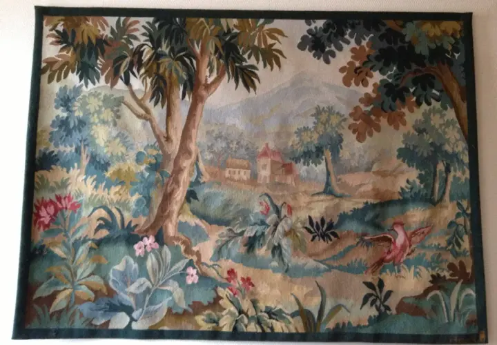 Magnifique toile d'Aubusson représentant un paysage champêtre avec des arbres, des fleurs et un oiseau rose en plein vol.