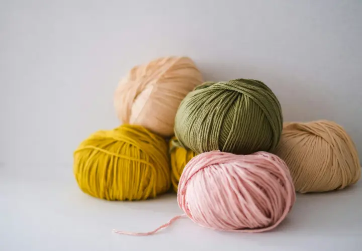 Pelotes de laine aux couleurs pastel, dont une rose pâle, une verte et une jaune. La matière semble être du nylon, parfaite pour des créations durables.
