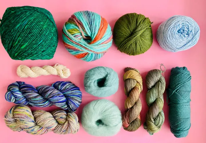 Assortiment de pelotes de laine aux couleurs vives et naturelles, évoquant l'origine de la laine et la beauté de la nature.