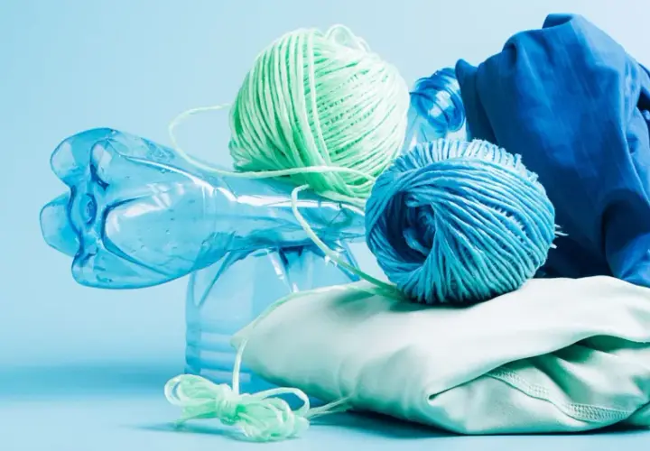 Bouteille en plastique bleue, pelotes de fil vert et bleu, et tissu bleu et vert pâle. Le fil est fait de polyester fiber, prêt à être recyclé.
