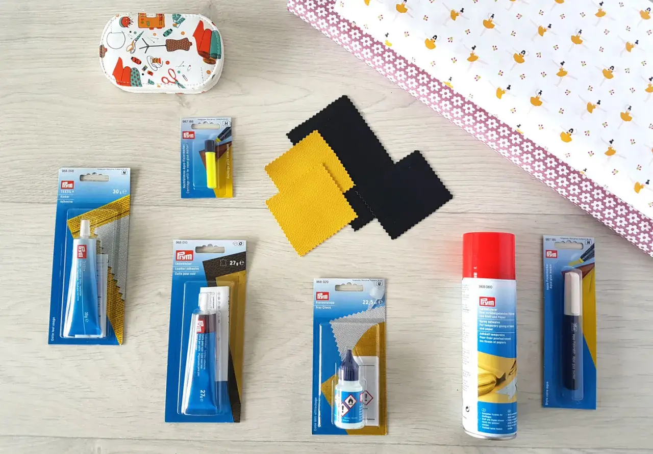 Matériel pour enlever colle sur tissu polyester : tubes de colle textile, cuir, spray adhésif, marqueur effaçable et tissu imprimé.