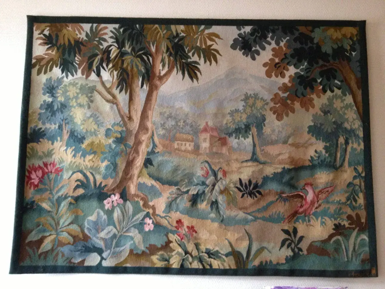 Magnifique toile d'Aubusson représentant un paysage champêtre avec des arbres, des fleurs et un oiseau rose en plein vol.