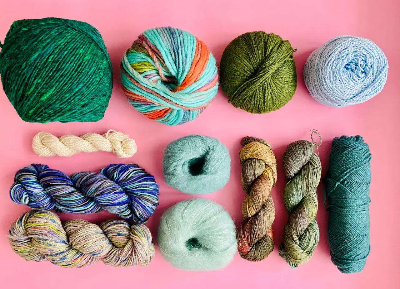 Assortiment de pelotes de laine aux couleurs vives et naturelles, évoquant l'origine de la laine et la beauté de la nature.